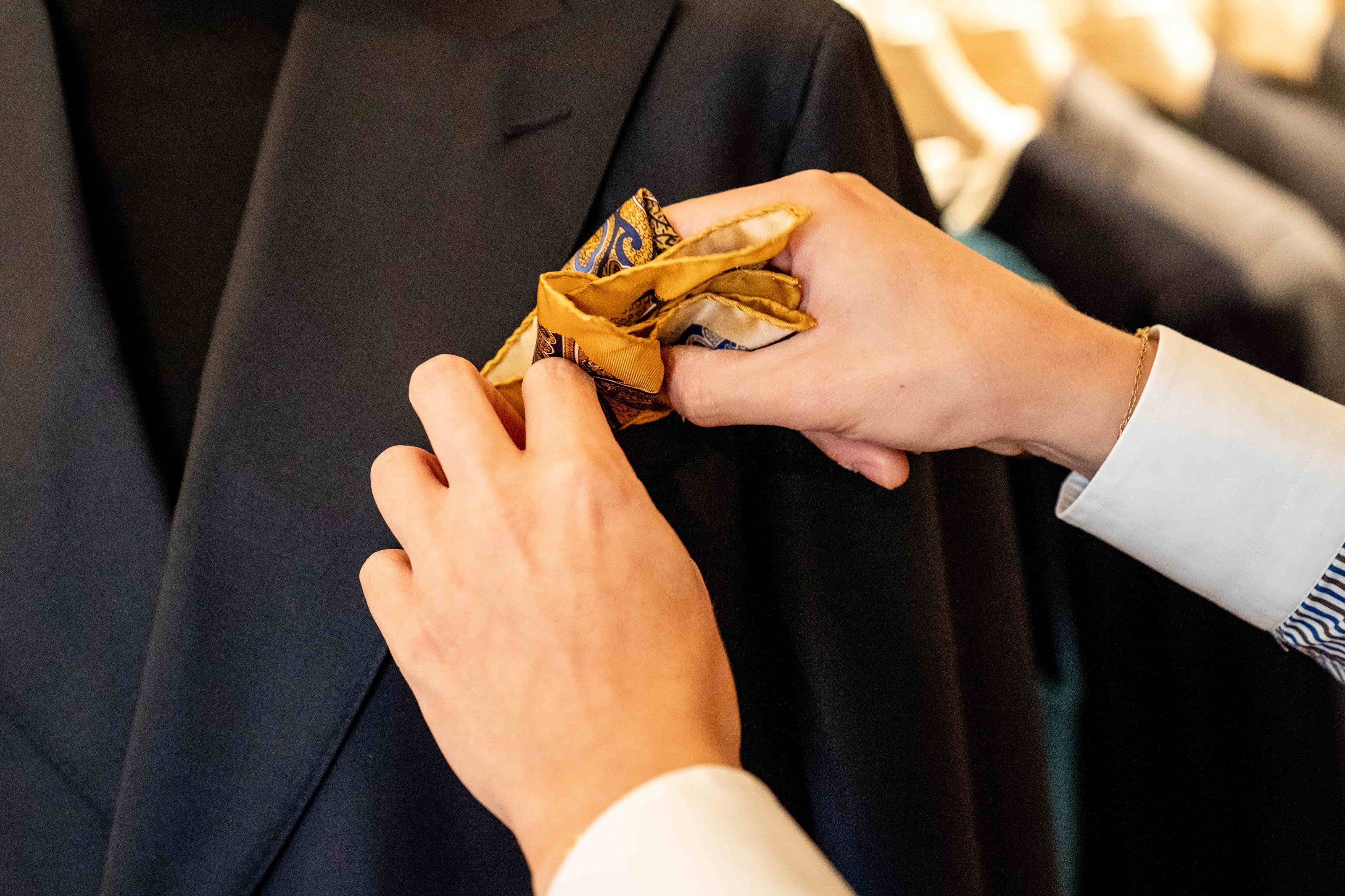 style-advisor-adjusting-a-pocket-square-placed-under-a-bespoke-jacket-peak-lapel