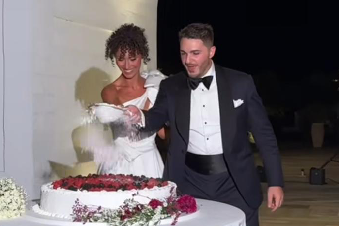 groom-tuxedo-attire-by-caprice-bespoke-and-woman-in-formal-attire-cutting-a-wedding-cake